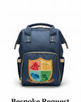 A navy blue diaper bag with a colorful shield graphic on the front pocket, resting on a white textured bedsheet.