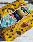 Yellow fabric bag with animal patterns containing colorful items on a wooden surface