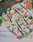 A close-up image of cloth pocket nappies in a woodland animals print, highlighting their adjustable snaps and sustainable materials.