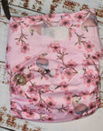 A photograph of cloth diaper pocket nappies and hemp boosters, illustrating their eco-friendly and adjustable design. features pink blossom and jay birds.