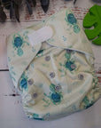 An image of cloth pocket nappies with hemp boosters neatly arranged on a flat surface. The nappies are made of soft, colorful fabric with elastic leg cuffs and snaps for adjustable sizing. The hemp boosters are slim inserts made from natural fibers, designed to enhance absorbency. This eco-friendly diapering option provides reusable and sustainable comfort for babies