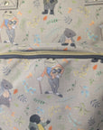 Close-up of a beige canvas tote bag with an all-over print of cartoon animals, including badgers, a frog, and a bird, in muted green, blue, orange, and gray tones.