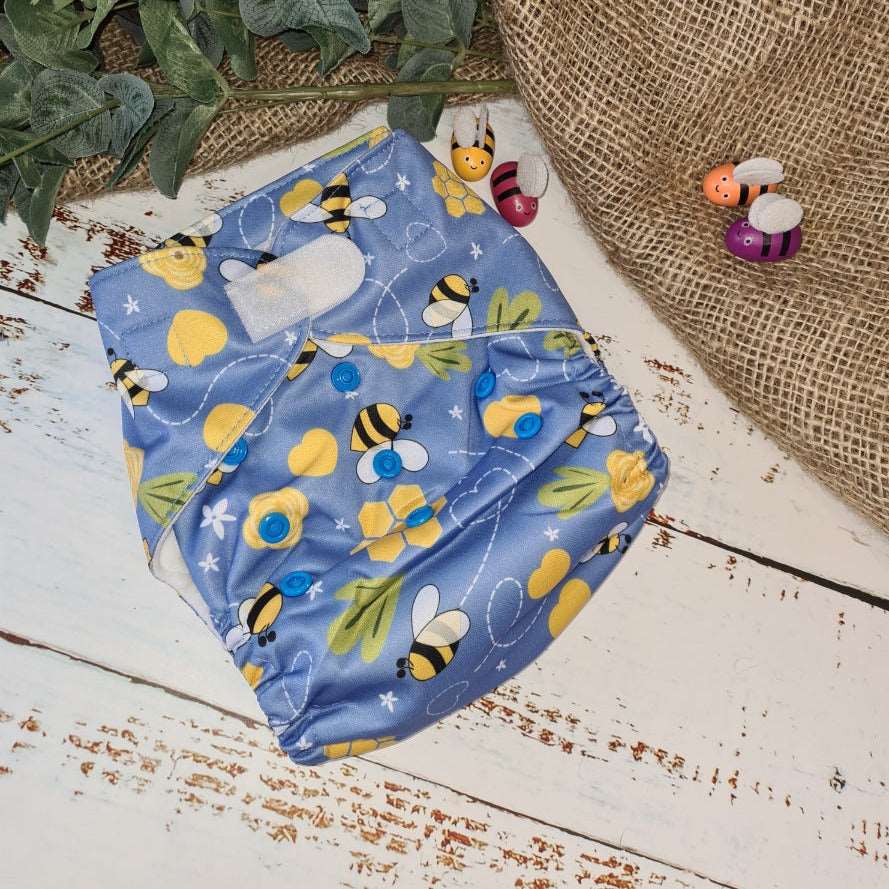 A photo of cloth pocket nappies in a bumble bee print featuring hemp boosters, showcasing an eco-friendly diapering choice with colorful, reusable fabrics 