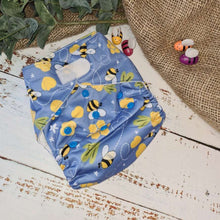 Load image into Gallery viewer, A photo of cloth pocket nappies in a bumble bee print featuring hemp boosters, showcasing an eco-friendly diapering choice with colorful, reusable fabrics 
