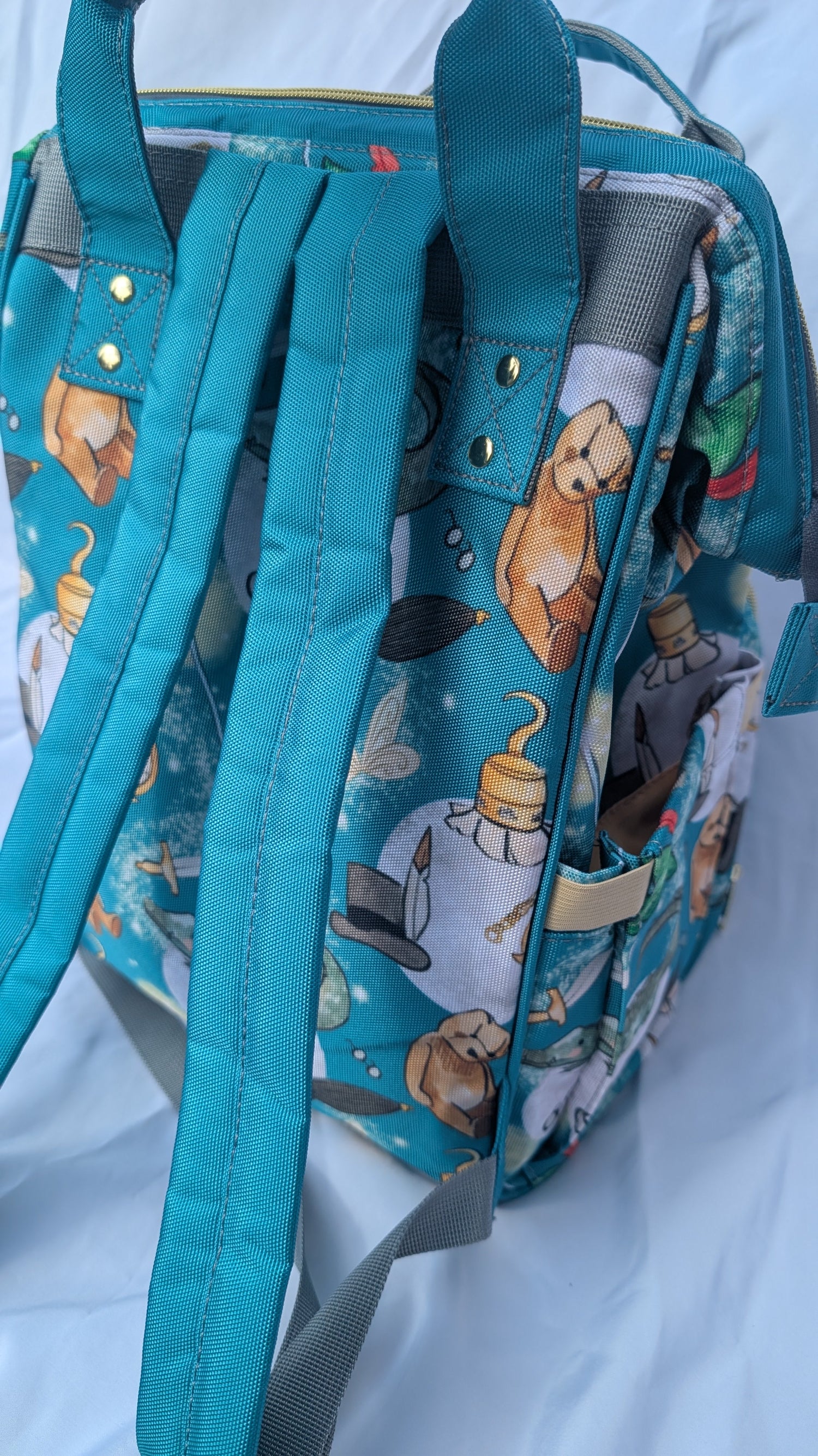 Back of teal backpack with cartoon characters pattern on a white background