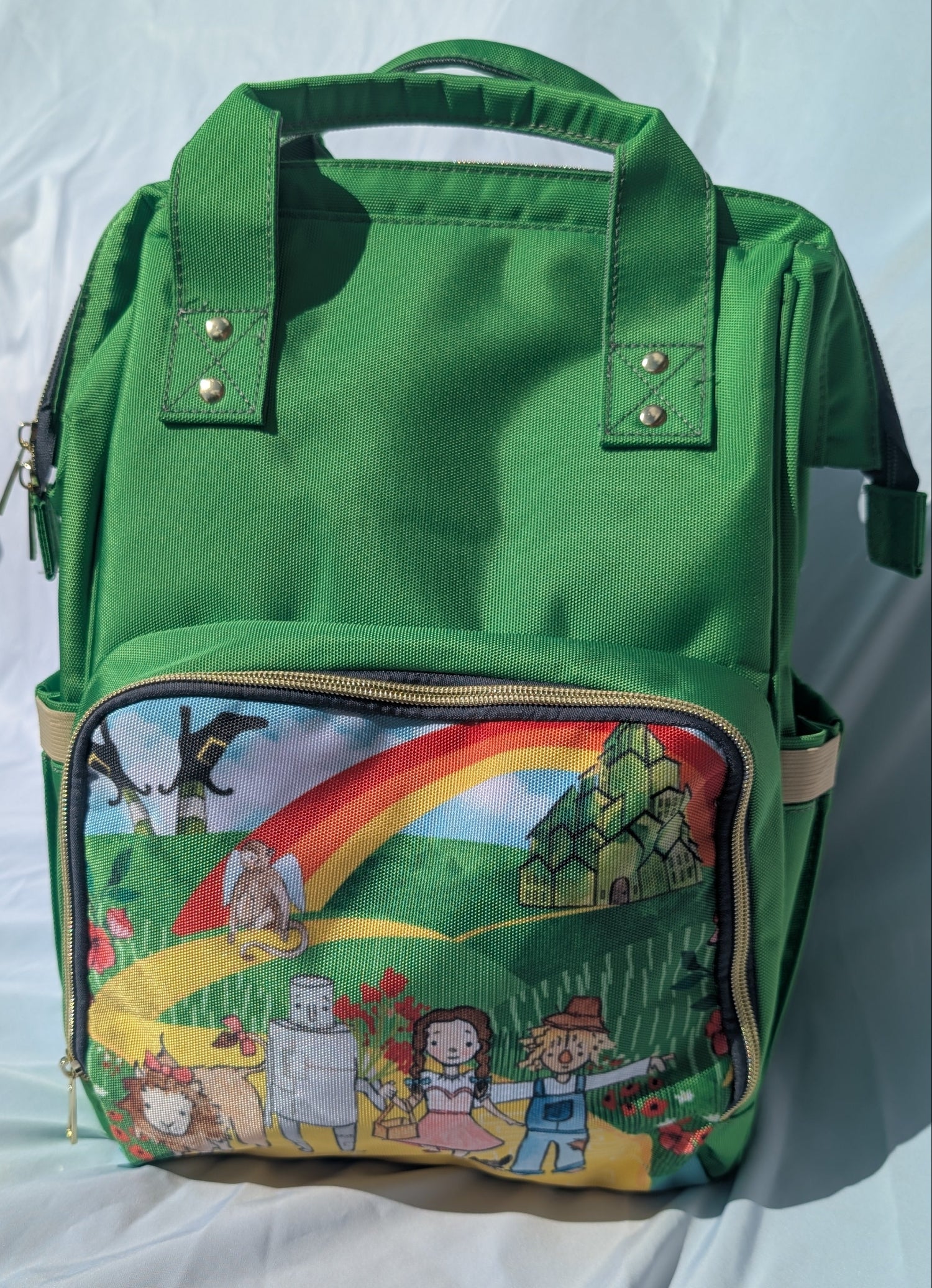 Green backpack with colorful cartoon design of the friends from Wizard of Oz