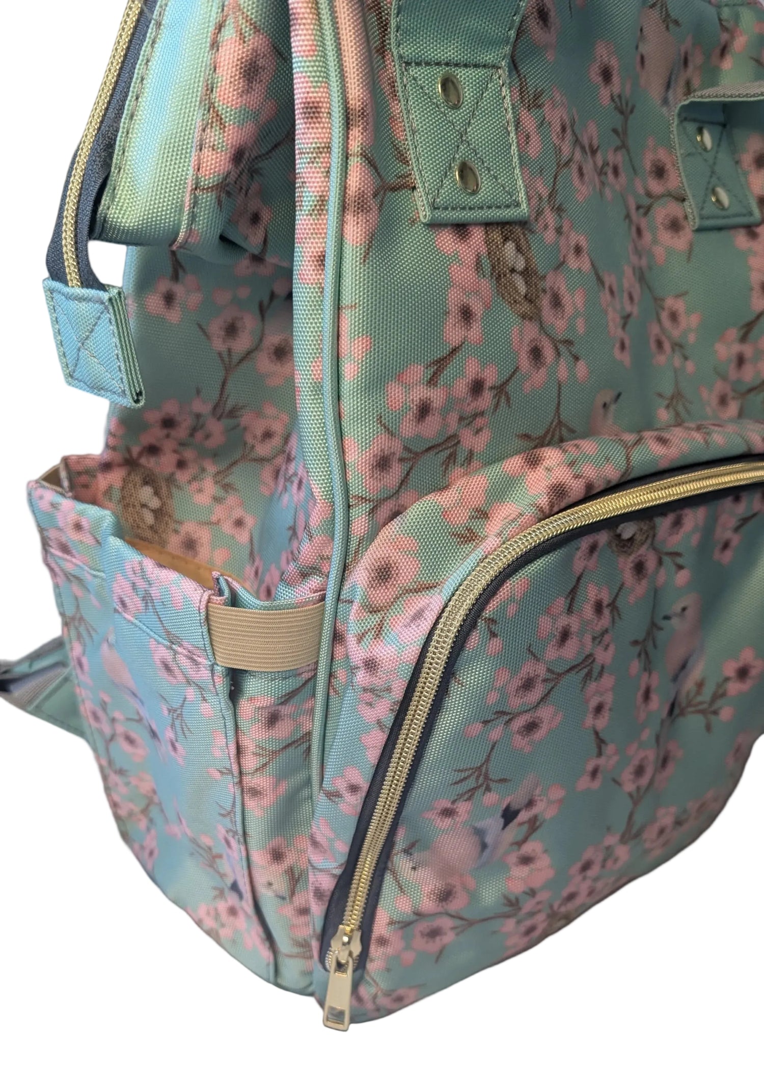 Floral-patterned bag with a gold zipper on a close up of a baby nappy changing bag
