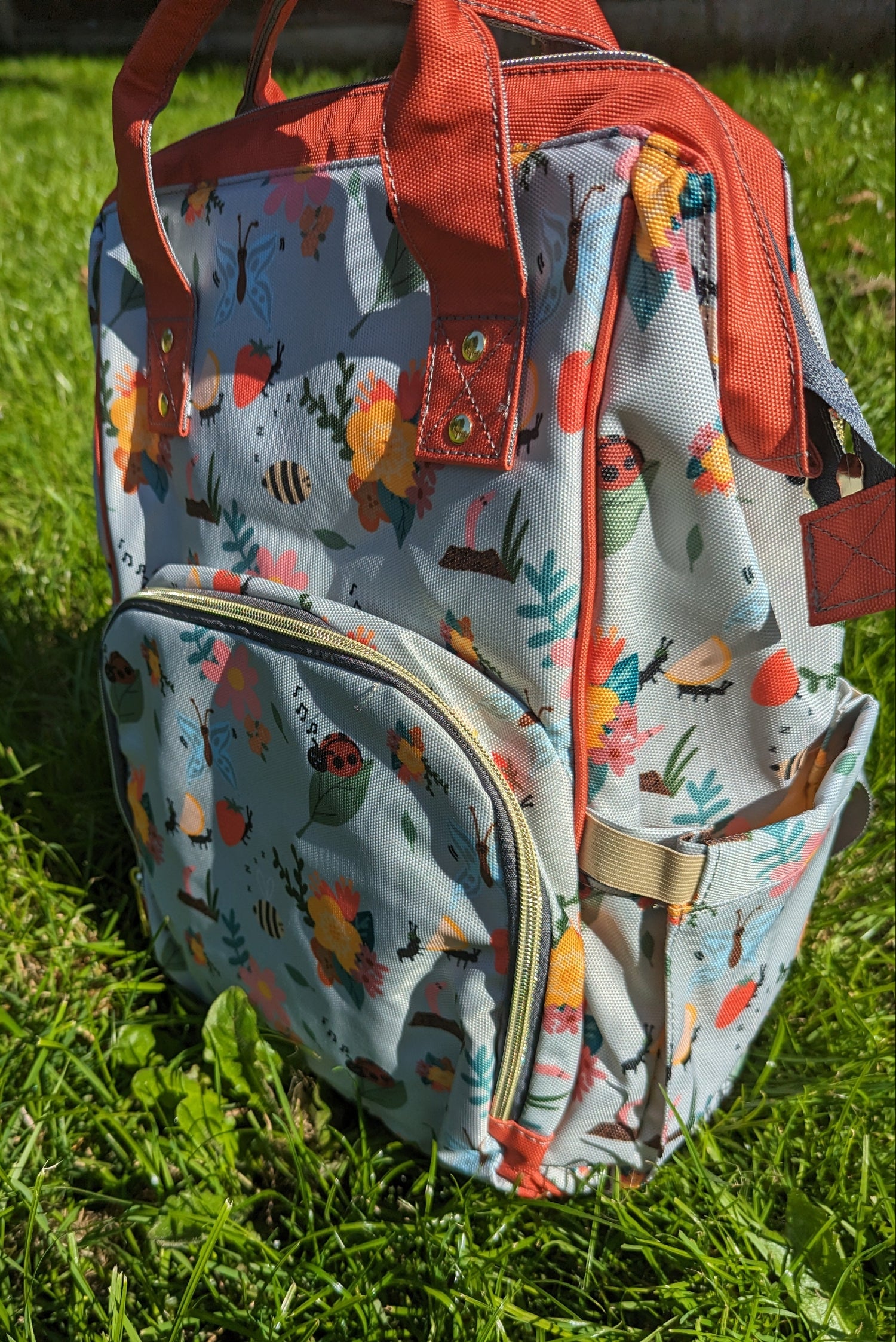 Floral-patterned baby changing backpack on grass
