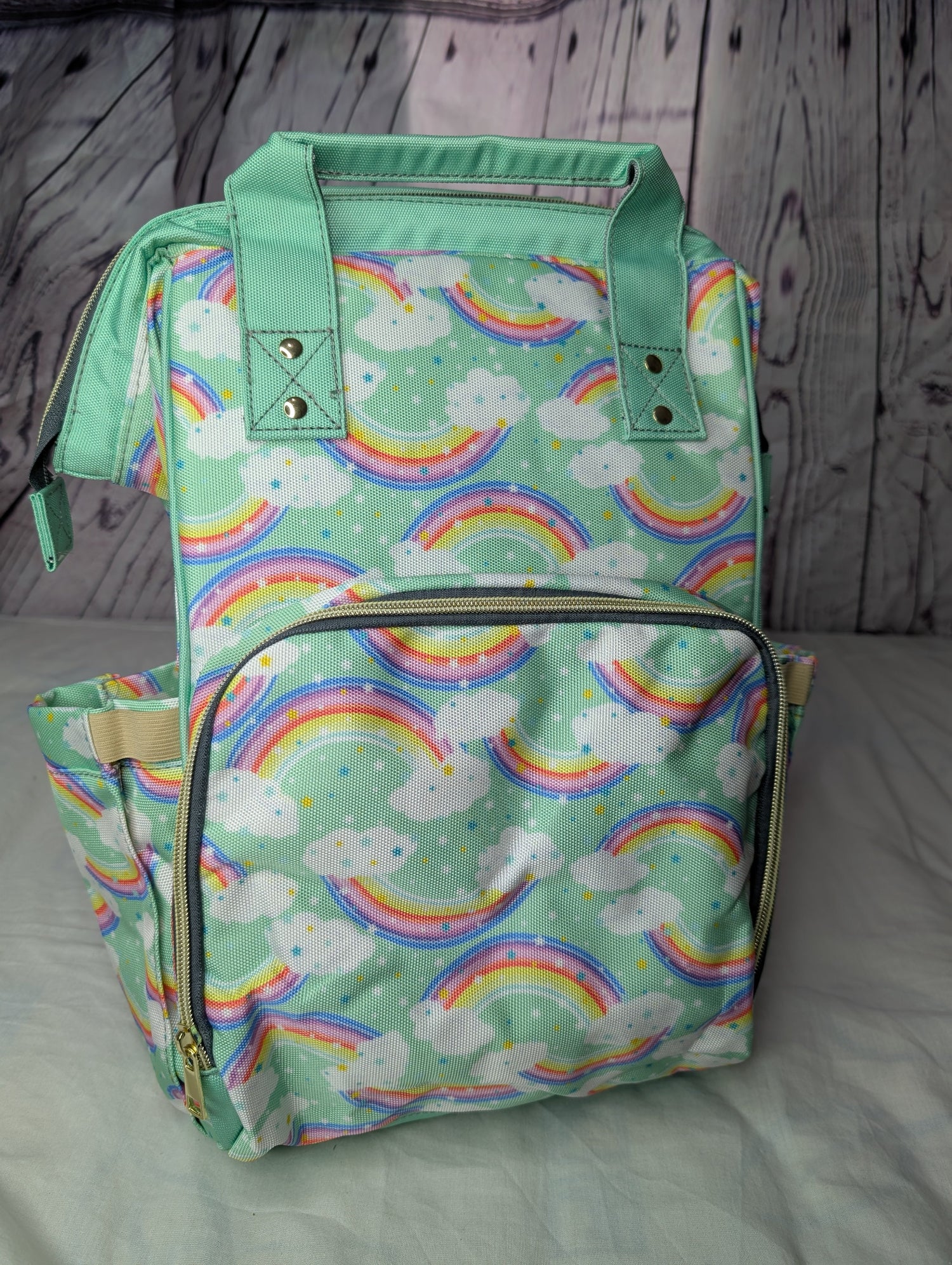 Parents Baby Backpack with rainbow and cloud pattern on a wooden surface