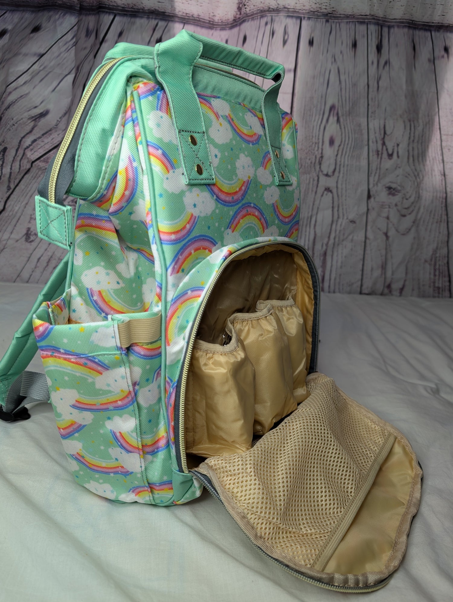 Parents baby changing bag Backpack with rainbow and cloud pattern on a wooden surface