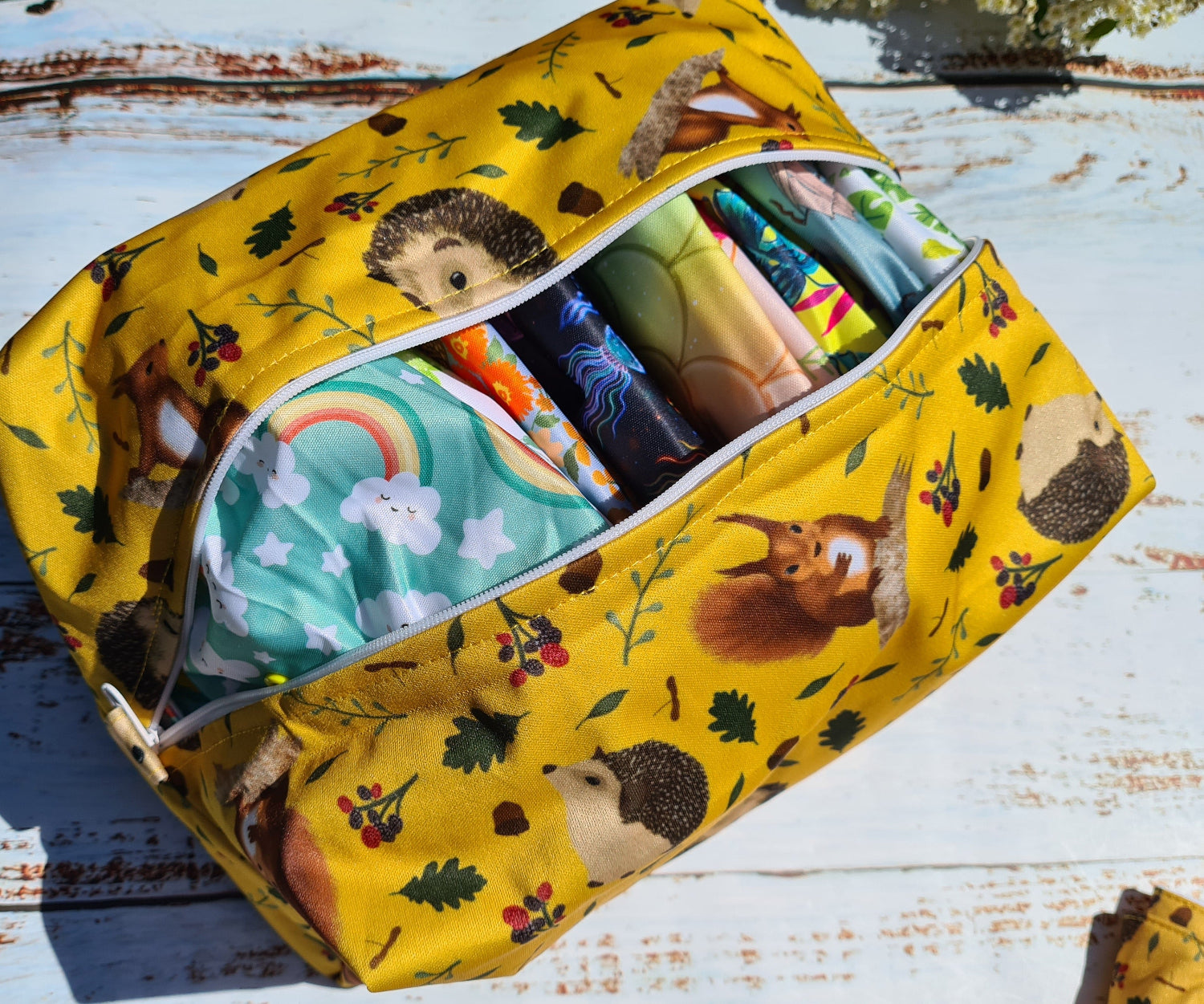 Yellow fabric bag with animal patterns containing colorful items on a wooden surface