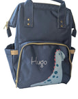 Navy blue backpack with a dinosaur design and 'Hugo' text on a white surface.
