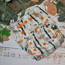 Load image into Gallery viewer, A close-up image of cloth pocket nappies in a woodland animals print, highlighting their adjustable snaps and sustainable materials.
