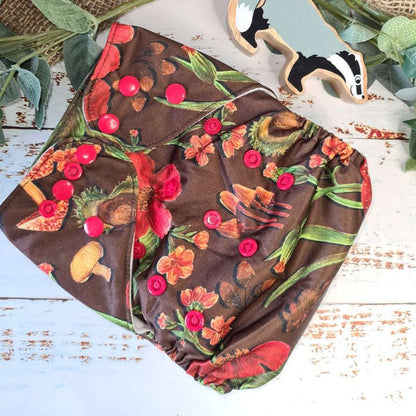 An overhead view of cloth pocket nappies and hemp boosters, an excellent choice for eco-conscious parents in a brown mushroom print