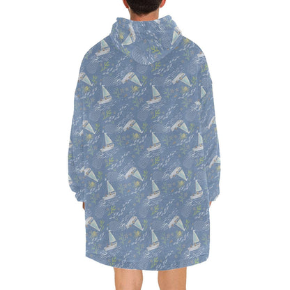 An Oodie-style hooded blanket with a charming blue boats print, designed to keep you warm and stylish on chilly days.