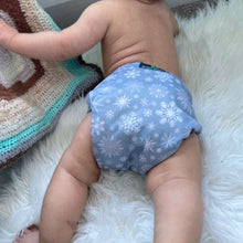 Load image into Gallery viewer, Green Cheeks Winter Cloth Nappy in a icey print is worn by a cute baby on fluffy white blanket
