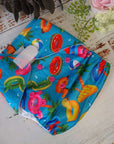 Cloth pocket nappies with hemp boosters in various vibrant colors, providing a sustainable way to keep babies comfortable and dry in blue with a pool party scene. 