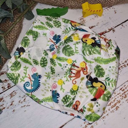 A close-up image of cloth pocket nappies with toucans, highlighting their adjustable snaps and sustainable materials.