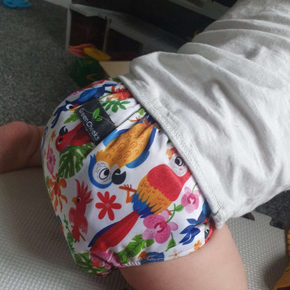 Cloth pocket nappies with hemp boosters in various vibrant colors, providing a sustainable way to keep babies comfortable and dry in a bright pink print with tropical birds