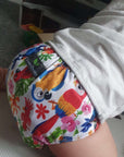 Cloth pocket nappies with hemp boosters in various vibrant colors, providing a sustainable way to keep babies comfortable and dry in a bright pink print with tropical birds