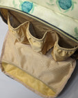 Floral-patterned bag with beige interior and mesh pocket on a light gray background