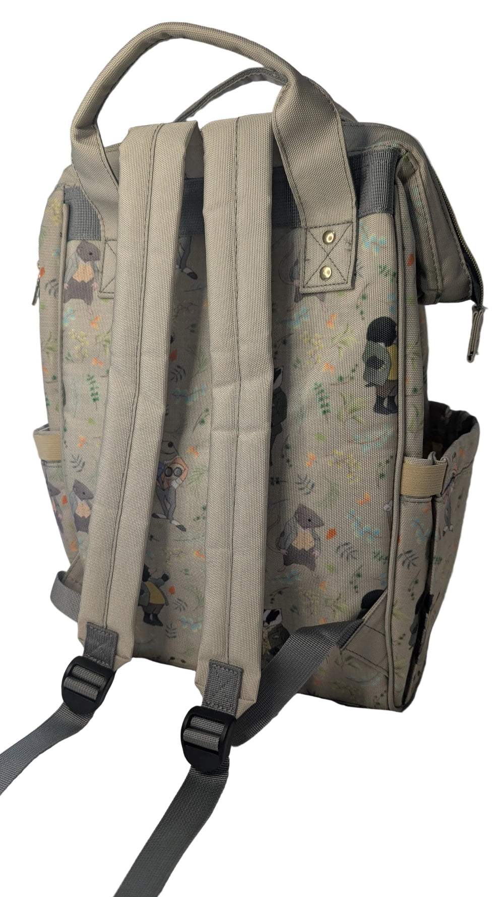 A light beige backpack with a delicate multicolor floral and character print, shown from the back with its padded shoulder straps resting on white bedding.