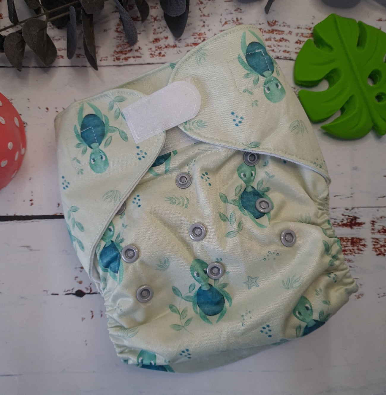 An image of cloth pocket nappies with hemp boosters neatly arranged on a flat surface. The nappies are made of soft, colorful fabric with elastic leg cuffs and snaps for adjustable sizing. The hemp boosters are slim inserts made from natural fibers, designed to enhance absorbency. This eco-friendly diapering option provides reusable and sustainable comfort for babies