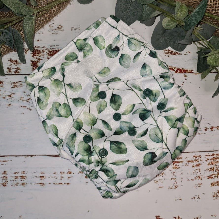 A Green Cheeks cloth nappy in botanical leaf print.