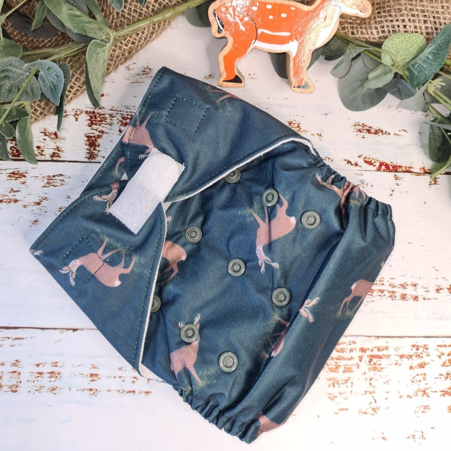 A picture of cloth washable pocket nappies with hemp boosters, featuring a woodland deer.