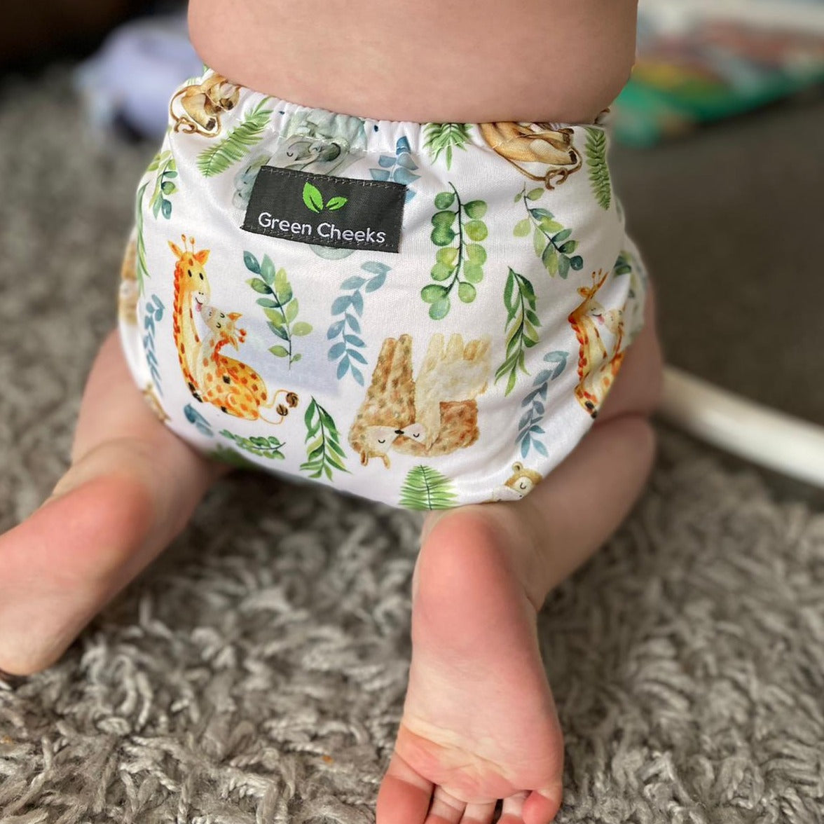 A baby wears a Green Cheeks Reusable Nappy. It has sleeping animals on the pattern.