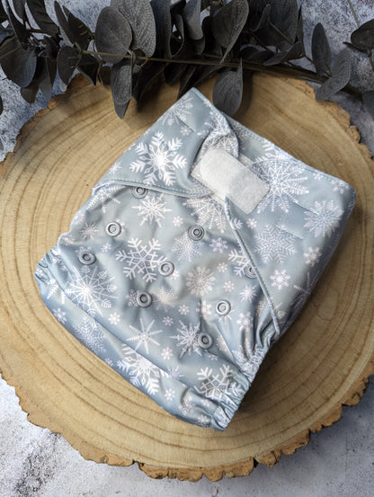 Christmas-themed cloth pocket nappies with festive patterns, featuring velcro fastening for easy and secure nappy changing